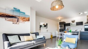 Un salon moderne avec un canapé gris, une table basse et un coin repas avec des chaises bleues.