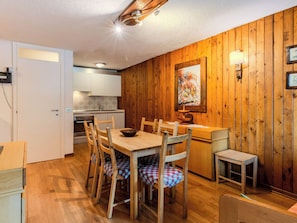 A wooden-paneled room with a dining table, chairs, a bench, a wall-mounted lamp, and a painting.