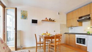 A compact living space with a dining area, kitchenette, and a sofa. - Apartment Apt 14 by Interhome (Canazei)