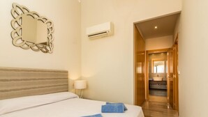 Ein Hotelzimmer mit Bett, Spiegel, Klimaanlage und einem sichtbaren Badezimmer durch eine geöffnete Tür.