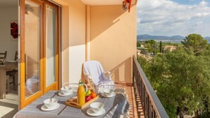 A balcony with a table set for breakfast, a chair, and a view of the landscape. - Les Mimosas by Interhome (Saint Aygulf)