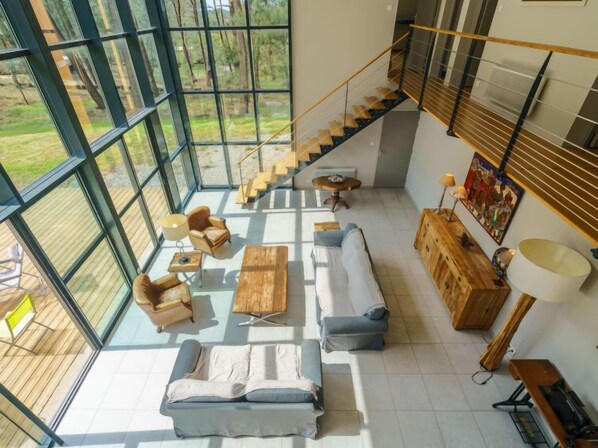 A spacious living area with a large window, a staircase, and a wooden cabinet.