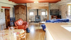 Ein gemütliches Wohnzimmer mit Kamin, Ledersofa, Esstisch und Fernseher.