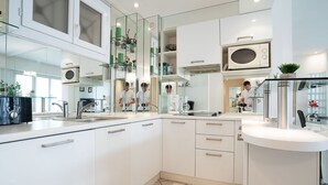 A modern kitchen with white cabinetry, a glass backsplash, and a built-in microwave. - Le Cheverny by Interhome (Cannes)