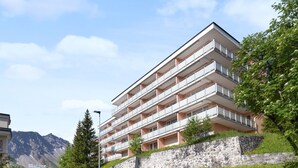 A multi-story hotel with balconies, situated on a hillside with a mountain backdrop. - Promenade Apt 216 by Interhome (Arosa)