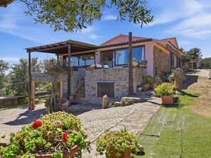 A stone house with a covered patio, stone steps, and potted plants.
