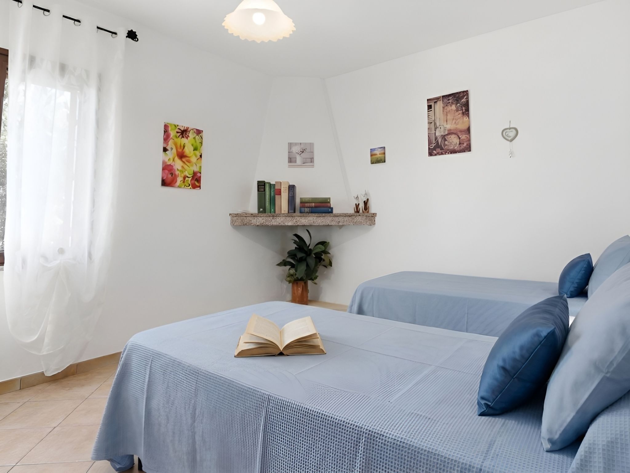Ein Schlafzimmer mit zwei Betten, einem Bücherregal und einem Fenster mit Vorhängen.