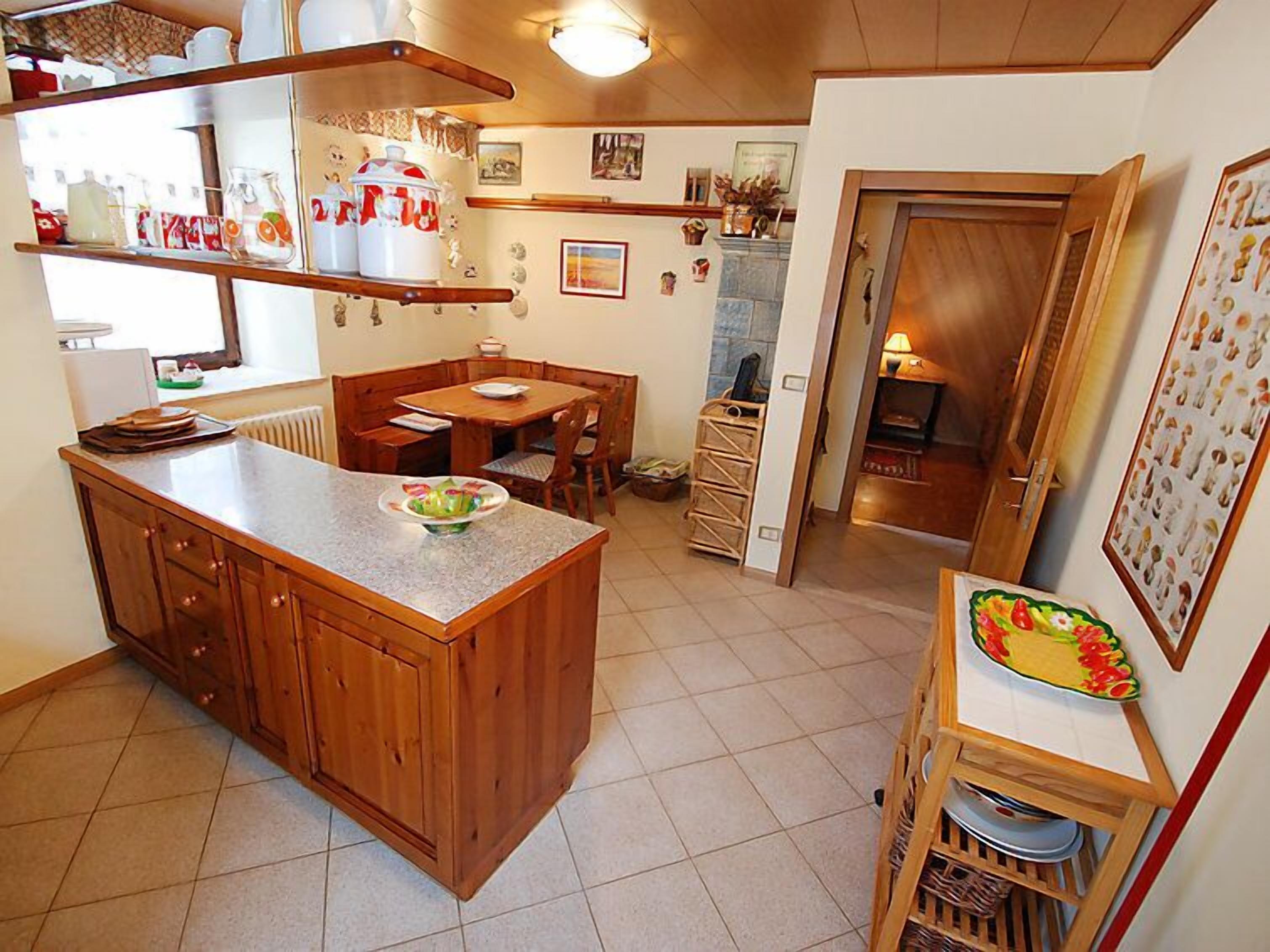 A kitchen with a central island, wooden cabinets, and a dining area with a table and chairs.