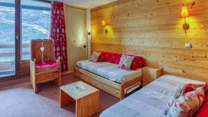 Een knus vertrek met een houten wand, een bank, een stoel en een bed.
