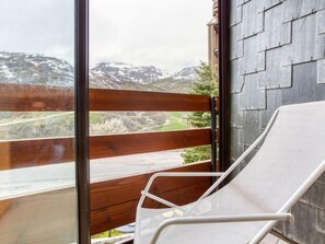 A balcony with a white chair, wooden railing, and a view of snow-capped mountains. - Chanteneige 301 by Interhome (Les Menuires)