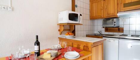 A compact kitchen with wooden cabinets, a microwave, a toaster, and a dishwasher.