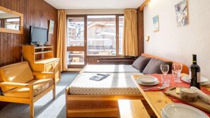 A cozy room with a bed, a wooden chair, a television, and a dining area with a table set for two. - Le Slalom (Val Claret) by Interhome (Tignes)