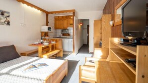 A compact room with a bed, a desk, a TV, and a kitchenette. - Le Slalom (Val Claret) by Interhome (Tignes)
