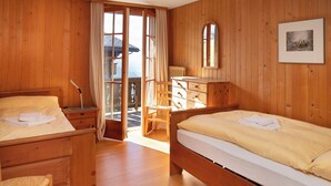 Una stanza in legno con due letti, una scrivania e una sedia.