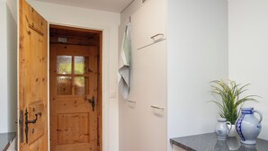 Una stanza con una porta in legno, un armadietto bianco con cassetti e un piano di lavoro con oggetti decorativi.