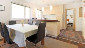 Habitación de hotel moderna con comedor, kitchenette y un baño visible a través de una puerta abierta.
