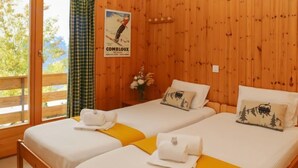 Ein Zimmer in einer Holzhütte mit zwei Betten, jeweils mit weißer Bettwäsche und gelben Akzenten.