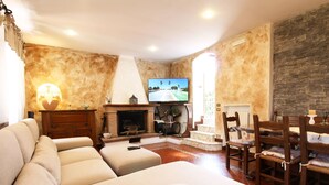 A living room with a fireplace, television, and a dining area with wooden furniture.