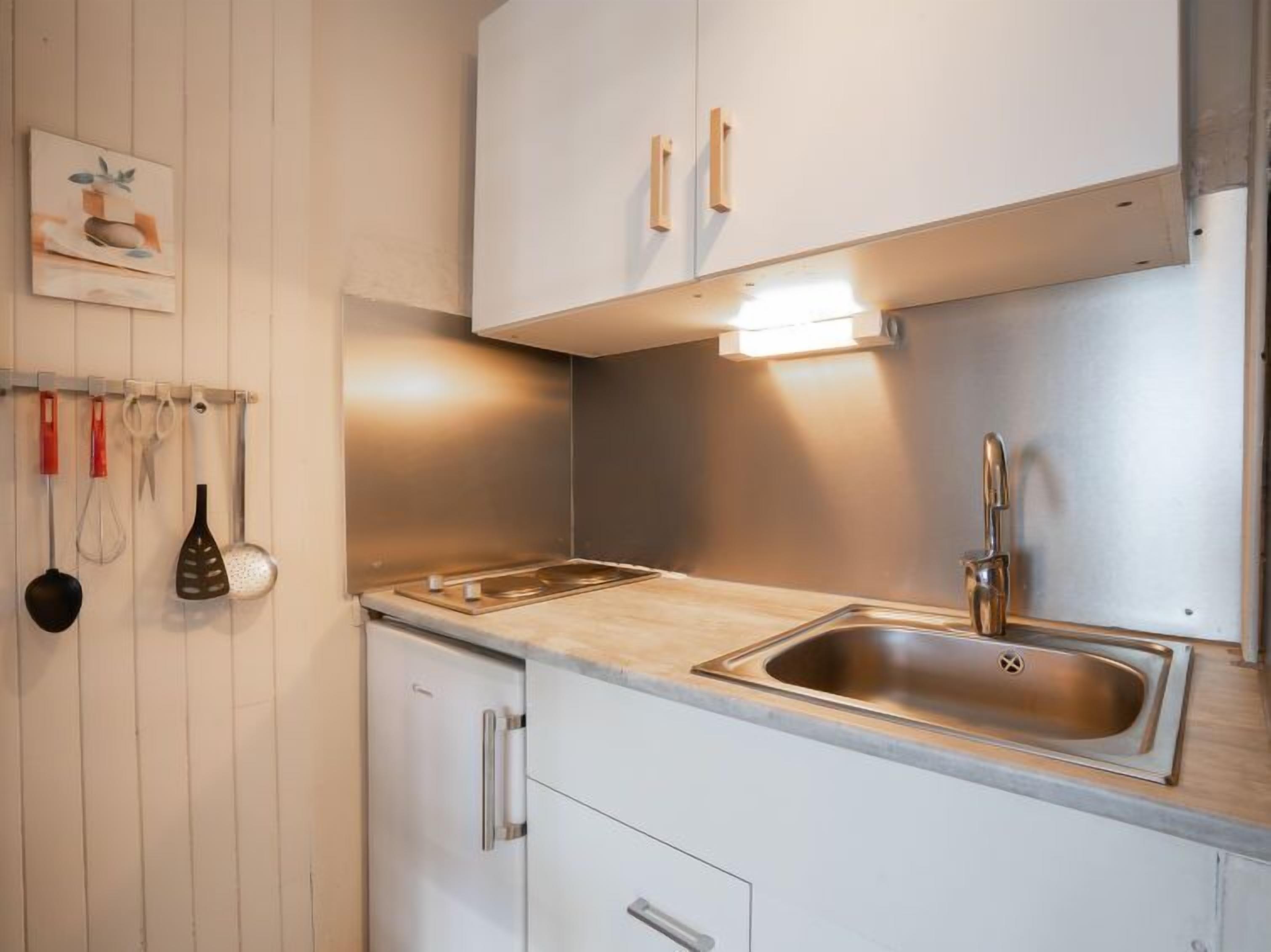 A modern kitchen with white cabinets, a stainless steel sink, and a light fixture above the countertop.