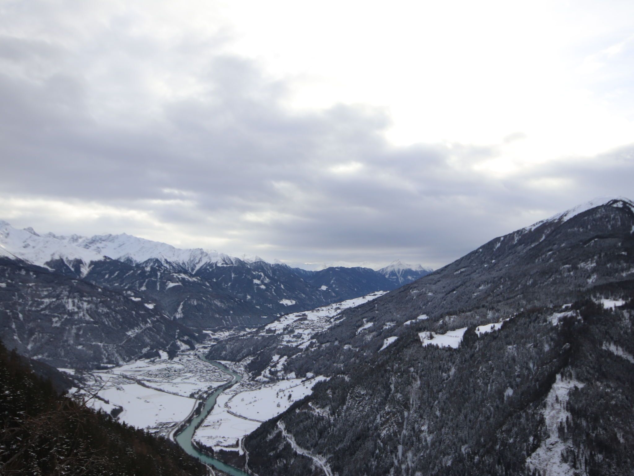 Eine Berglandschaft mit schneebedeckten Gipfeln und einem Fluss, der durch ein Tal fließt.