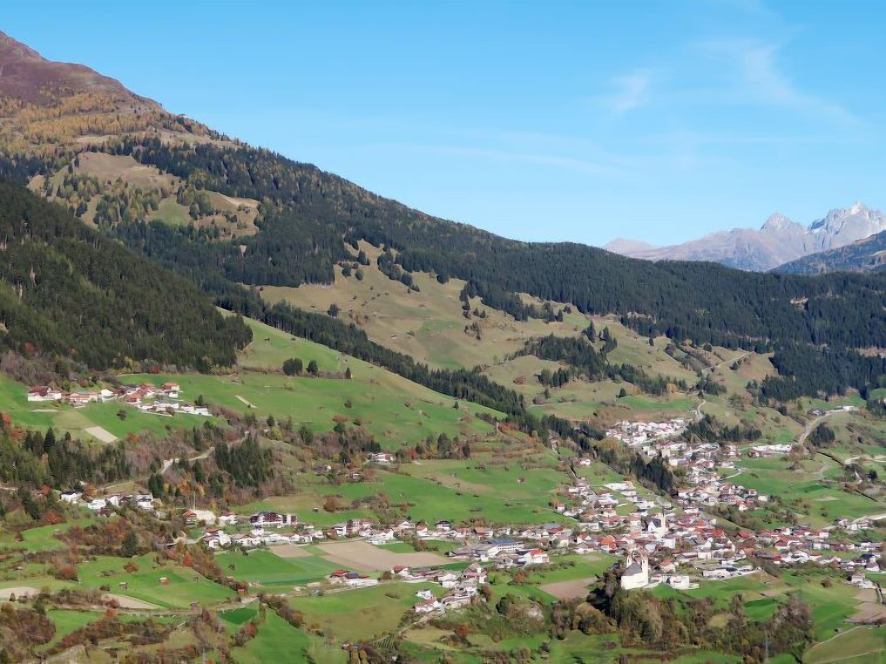 Un piccolo paese situato in una valle, con campi verdi e case sparse.