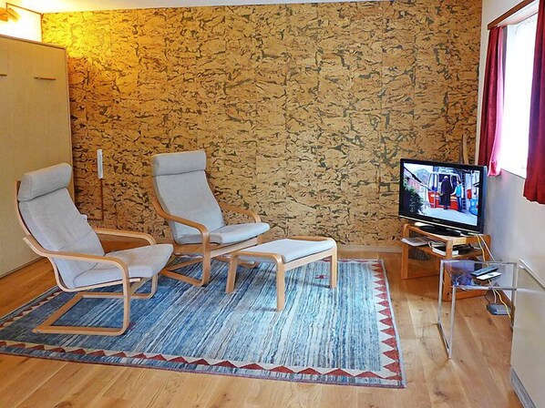 Un salon avec deux fauteuils, un téléviseur et un mur décoré d’un motif.
