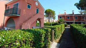 A pink building with a balcony, surrounded by greenery and a pathway. - Michelangelo by Interhome (Bibione)