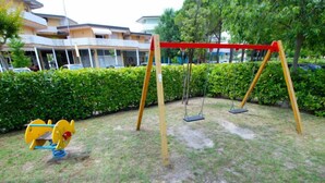 A playground with swings and a yellow and blue seesaw. - Michelangelo by Interhome (Bibione)