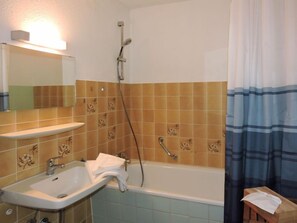 Un baño con lavamanos, espejo, ducha y toallero.