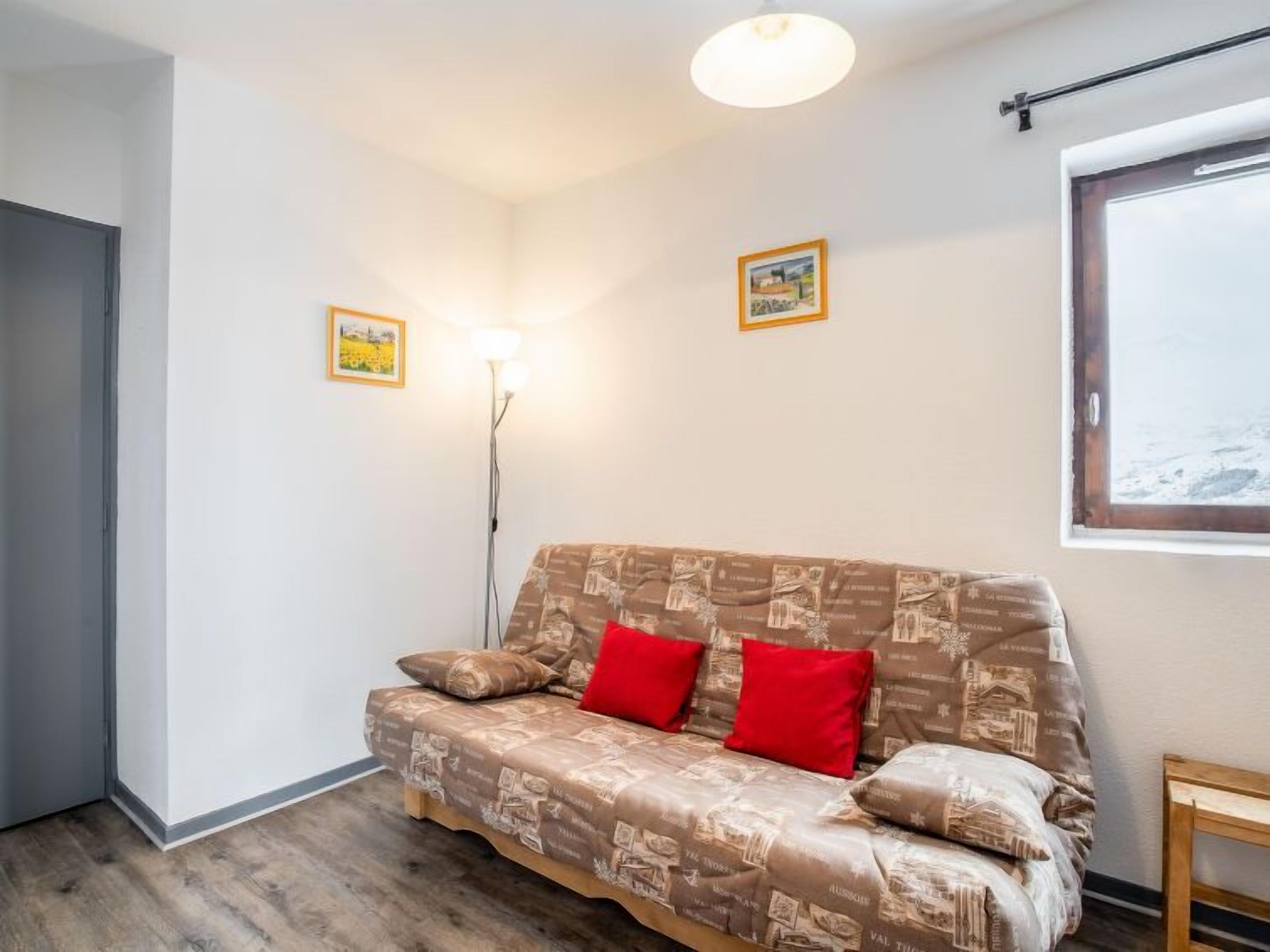 Ein gemütliches Zimmer mit einer gemusterten Couch, einer Stehlampe und einem Fenster mit Blick.