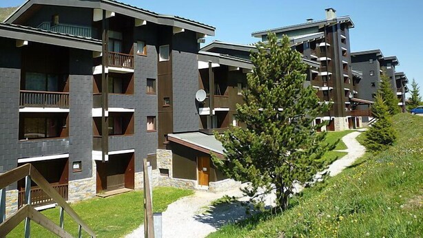 Un immeuble moderne à plusieurs étages, doté de balcons, d’une façade en pierre et surplombant un ciel dégagé.