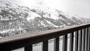 Un paysage de montagne enneigé, avec une rambarde en bois au premier plan.