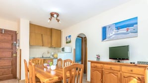 A compact living space with a dining area, kitchenette, and a television.