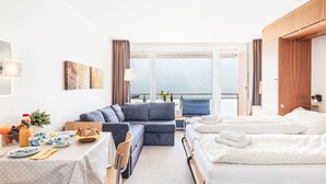 A hotel room with a bed, a sofa, a dining table with chairs, and a balcony with a view. - Promenade Apt 111 by Interhome (Arosa)