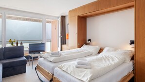 A modern hotel room with a large bed, a desk, a chair, and a TV. - Promenade Apt 111 by Interhome (Arosa)