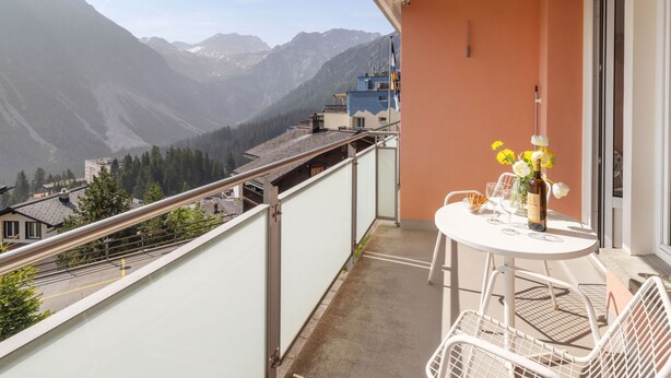 A balcony with a table and chairs, overlooking a mountainous landscape. - Promenade Apt 111 by Interhome (Arosa)