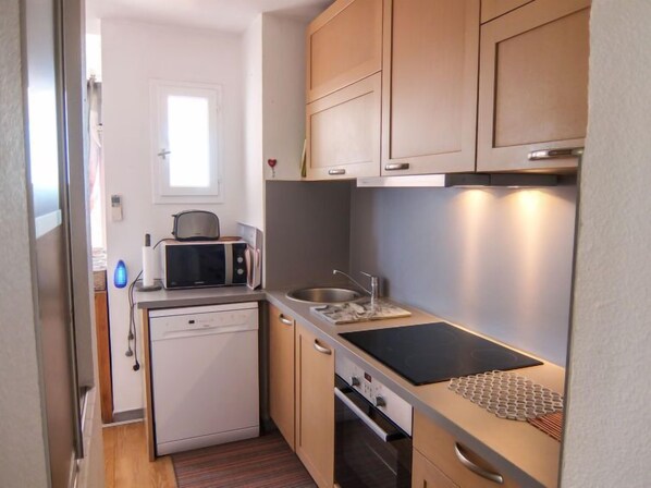 A compact kitchen with a microwave, toaster, sink, and a small oven.