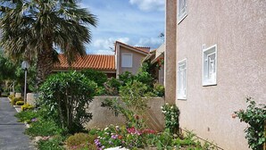Ein Wohngebäude mit Stuckfassade, einem Ziegeldach und einem kleinen Balkon mit Topfpflanzen.