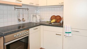 A kitchen with white cabinets, a stove, and a sink. - Mangeng by Interhome (Schruns)