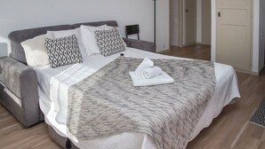 A neatly made bed with a patterned bedspread, two pillows with a geometric design, and a folded towel on the bed. - Diure 0113 by Interhome (Verbier)