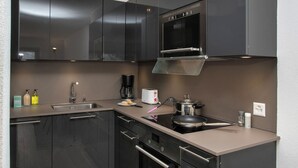 A modern kitchen with dark cabinets, a stainless steel oven, and a built-in microwave. - Diure 0113 by Interhome (Verbier)