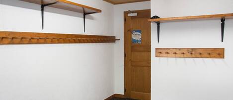 A hallway with wooden shelves, a door with a sign, and a textured floor.