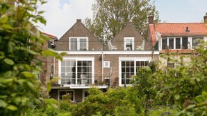 A two-story house with a brick facade, large windows, and a garden in the foreground.