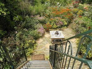 A garden with a stone pathway leading to a table with a decorative urn.