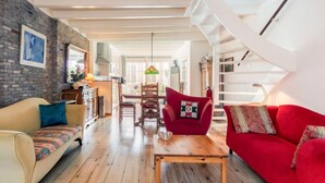 A spacious living room with a wooden floor, a red sofa, a beige sofa, and a wooden coffee table.