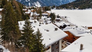 Ein schneebedecktes Dorf mit Häusern, einem Berg im Hintergrund und einem zugefrorenen See.