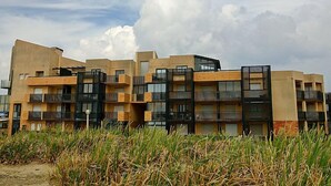 A modern multi-story residential building with balconies and a flat roof.