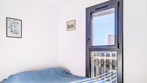 A bedroom with a bed, a window, and two framed pictures on the wall.