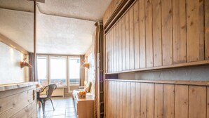 Ein Hotelzimmer mit Holzwänden, Fliesenboden, einem Schreibtisch mit Stuhl und einem Fenster mit Blick.