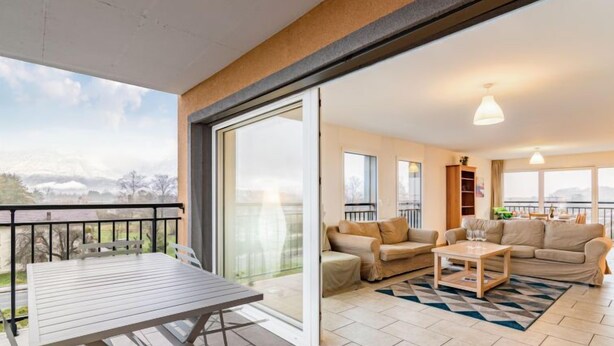 Ein großzügiger Wohnbereich mit Balkon, einer Sofagarnitur, einem Couchtisch und einem Esstisch.